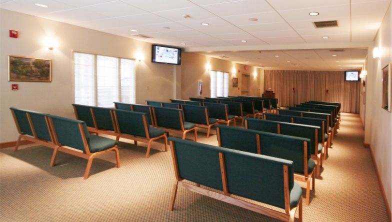 A waiting room with rows of blue chairs and a television on the wall