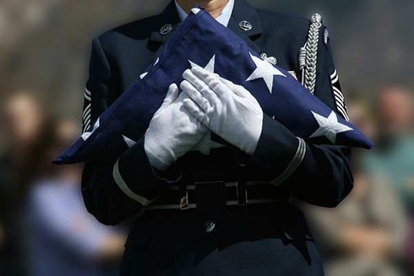 a man in a military uniform is holding an american flag