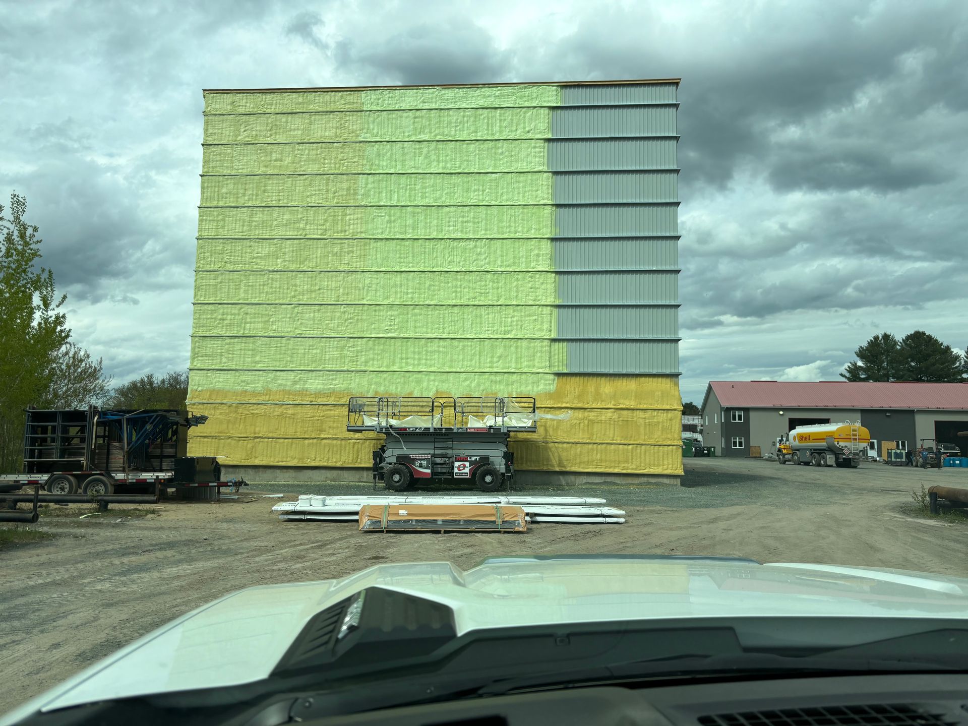 Construction de murs extérieurs avec isolation, partiellement recouvert de bardage gris, ciel nuageux.