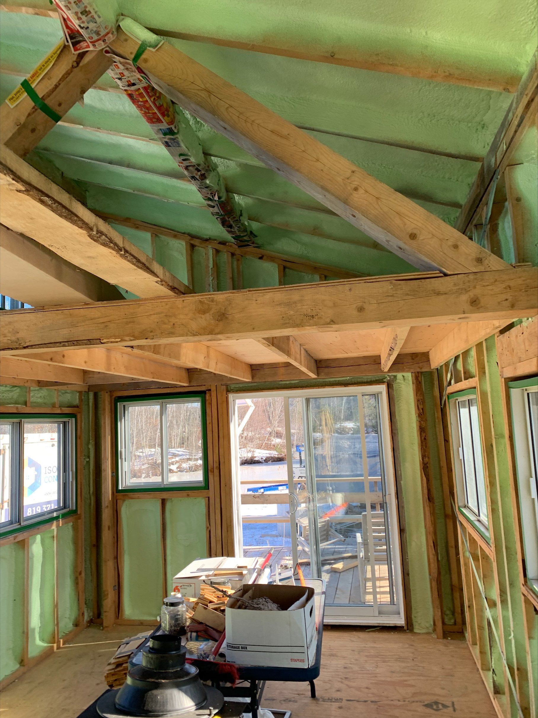 Intérieur d'une structure à ossature bois, avec isolation visible entre les poutres et les murs.