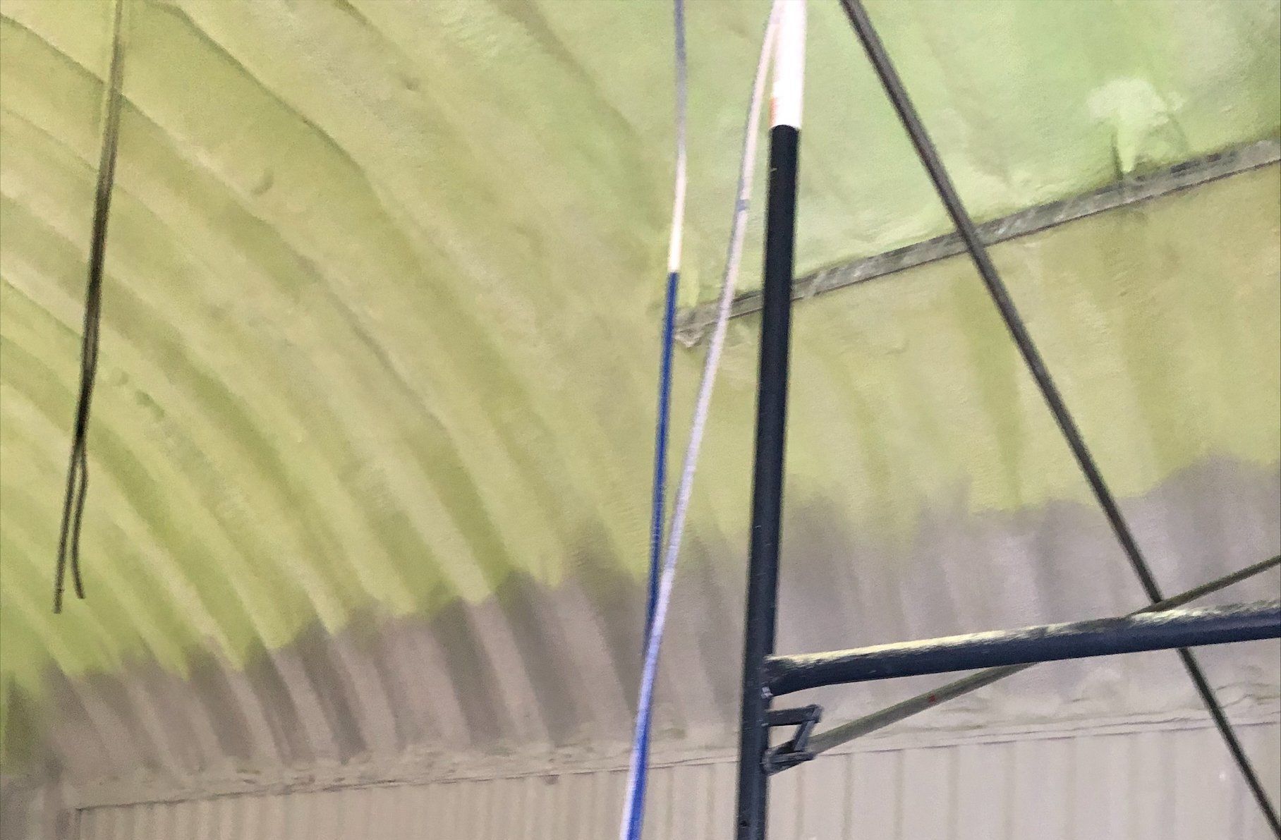 Un plafond incurvé avec des moisissures, des poutres métalliques et un poteau bleu et blanc.