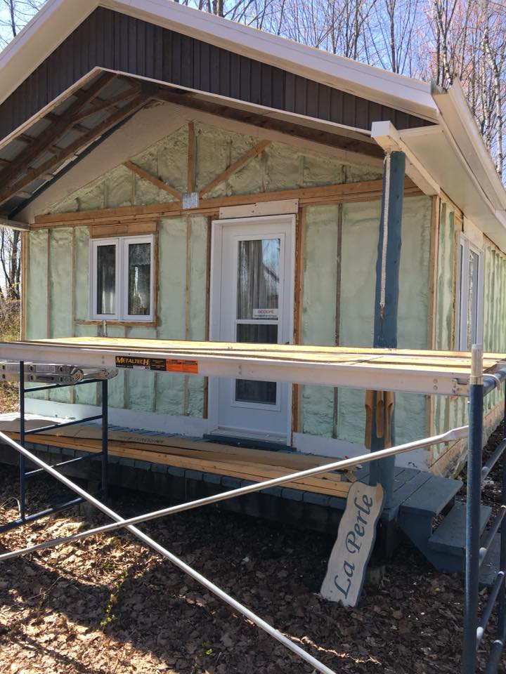 Extérieur de la cabine avec isolation en mousse pulvérisée exposée, échafaudage devant, panneau indiquant « La Perle ».