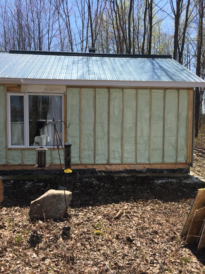 Une petite cabane avec un toit en tôle ondulée et une isolation apparente sur le mur extérieur.