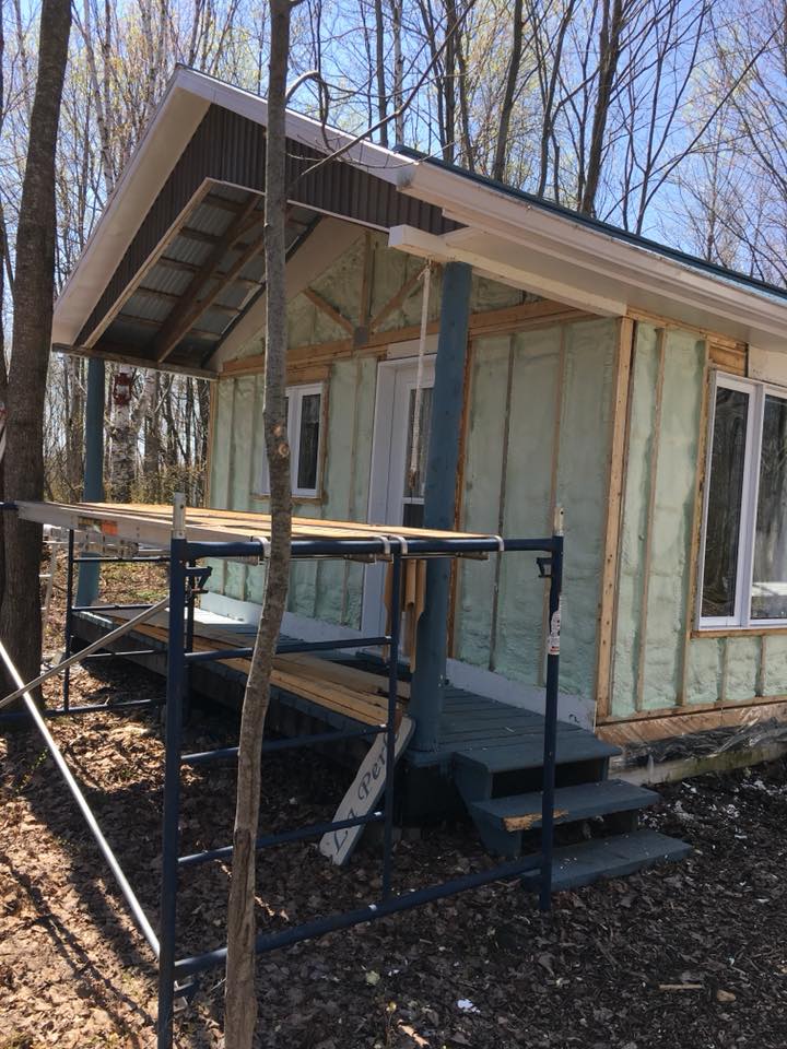 Cabane en construction avec isolation verte et échafaudage.
