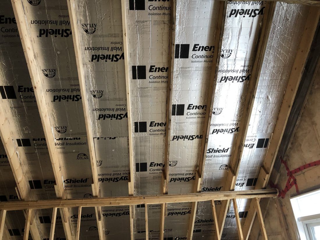 Chevrons en bois avec isolation réfléchissante installés dans un plafond.