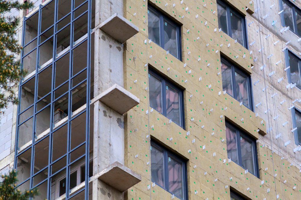 Bâtiment en construction avec isolation, fenêtres et cadres de balcon.