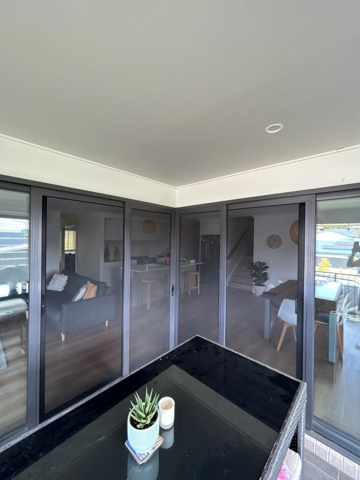 A Corner of A Patio with Black Sliding Doors — Envy Glass in Urunga, NSW