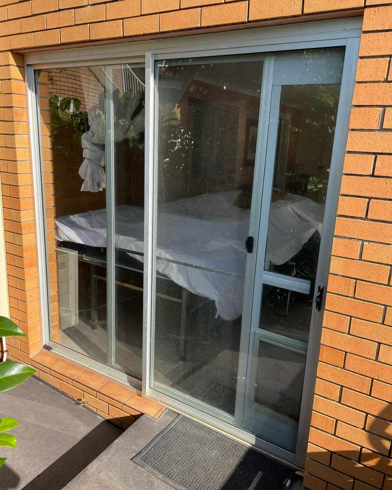 A Sliding Glass Door with A Table Covered — Envy Glass in Nambucca Heads, NSW