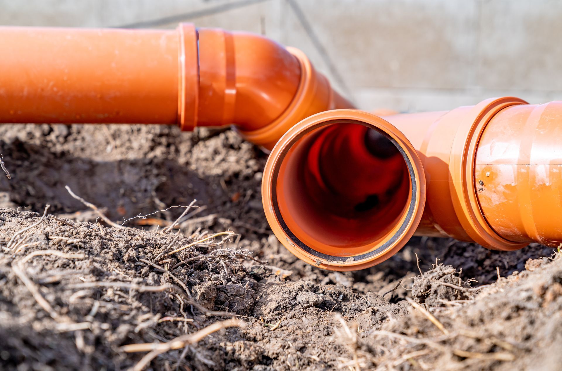 A couple of orange pipes laying in the dirt.