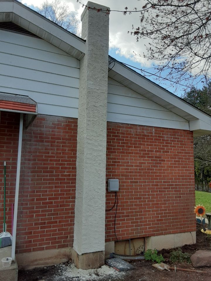 Brick house exterior with a white chimney and gray siding under a blue sky