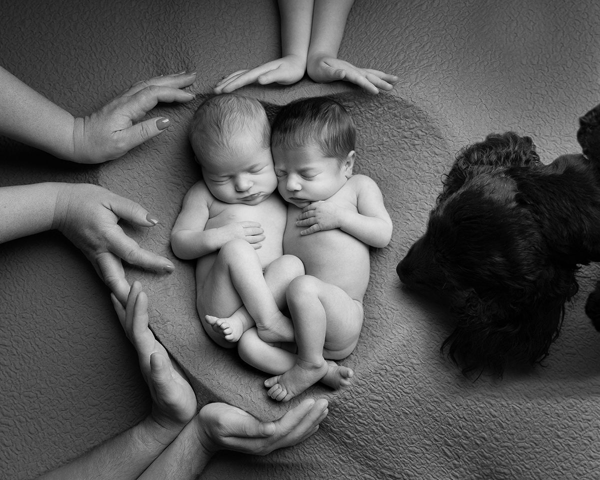 Newborn baby sleeping peacefully in heart-shaped bed of soft, cream-colored fur surrounded by flowers.