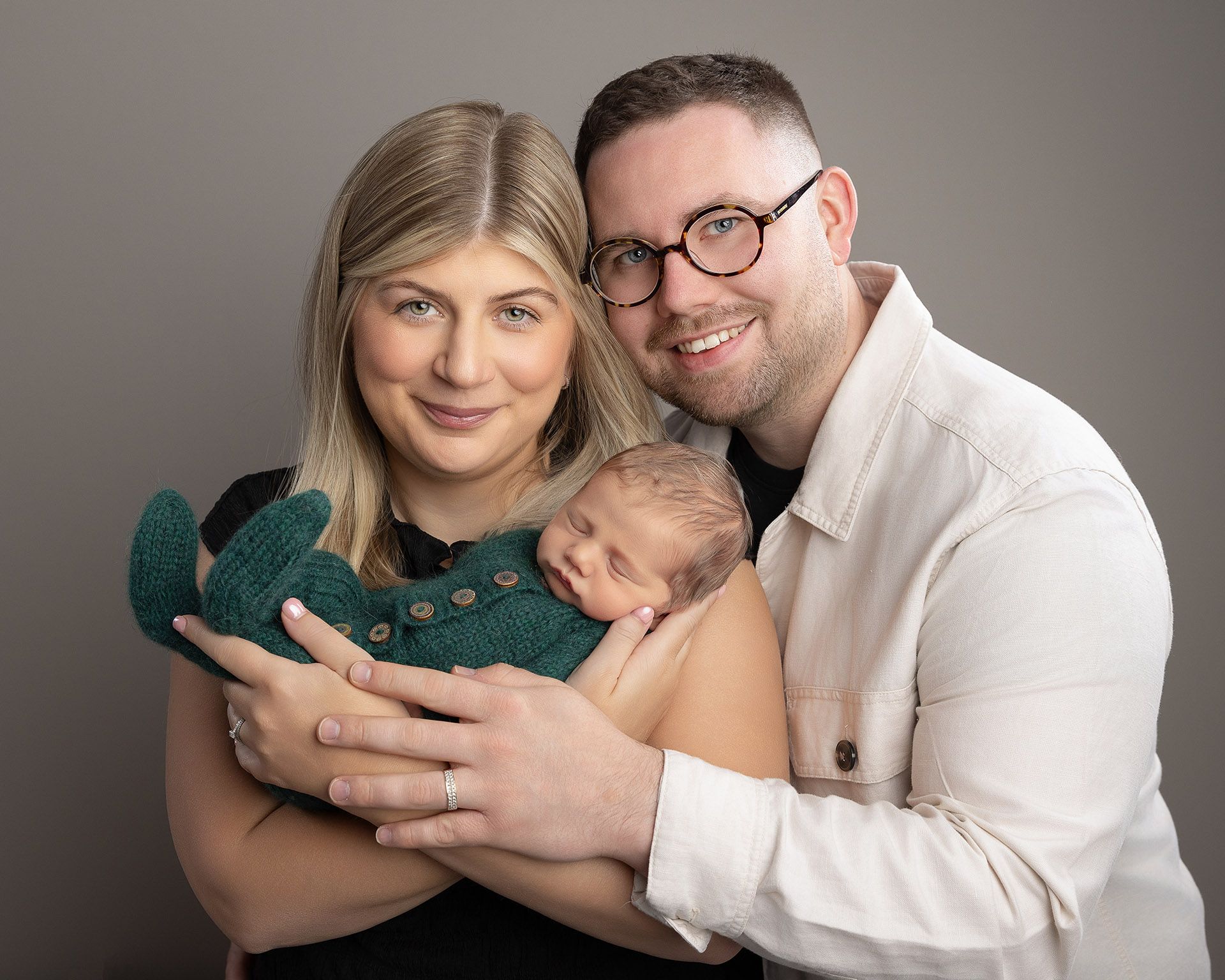 A man and woman are holding a newborn baby in their arms.