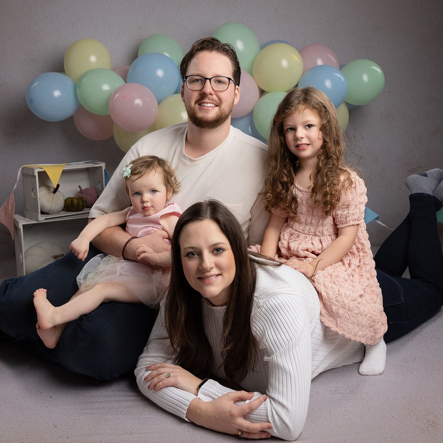 A family is posing for a picture with balloons in the background.