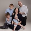 Family portrait: Parents and three children smiling, light background.