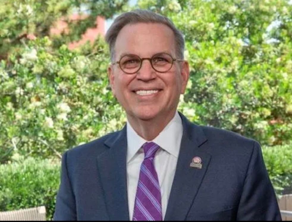 A man in a suit and tie is smiling for the camera.