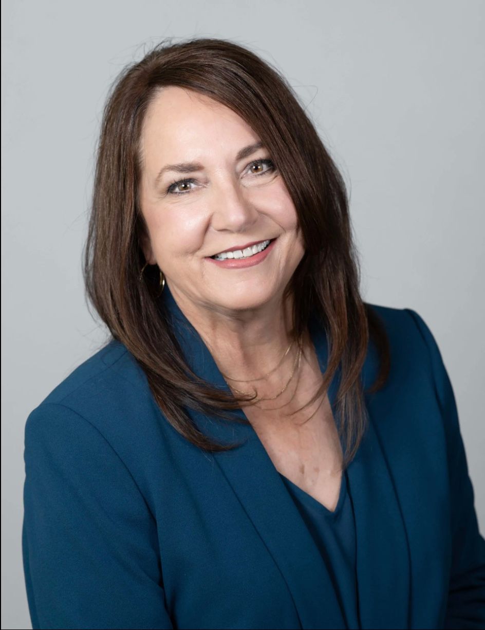 A woman in a blue jacket is smiling for the camera.