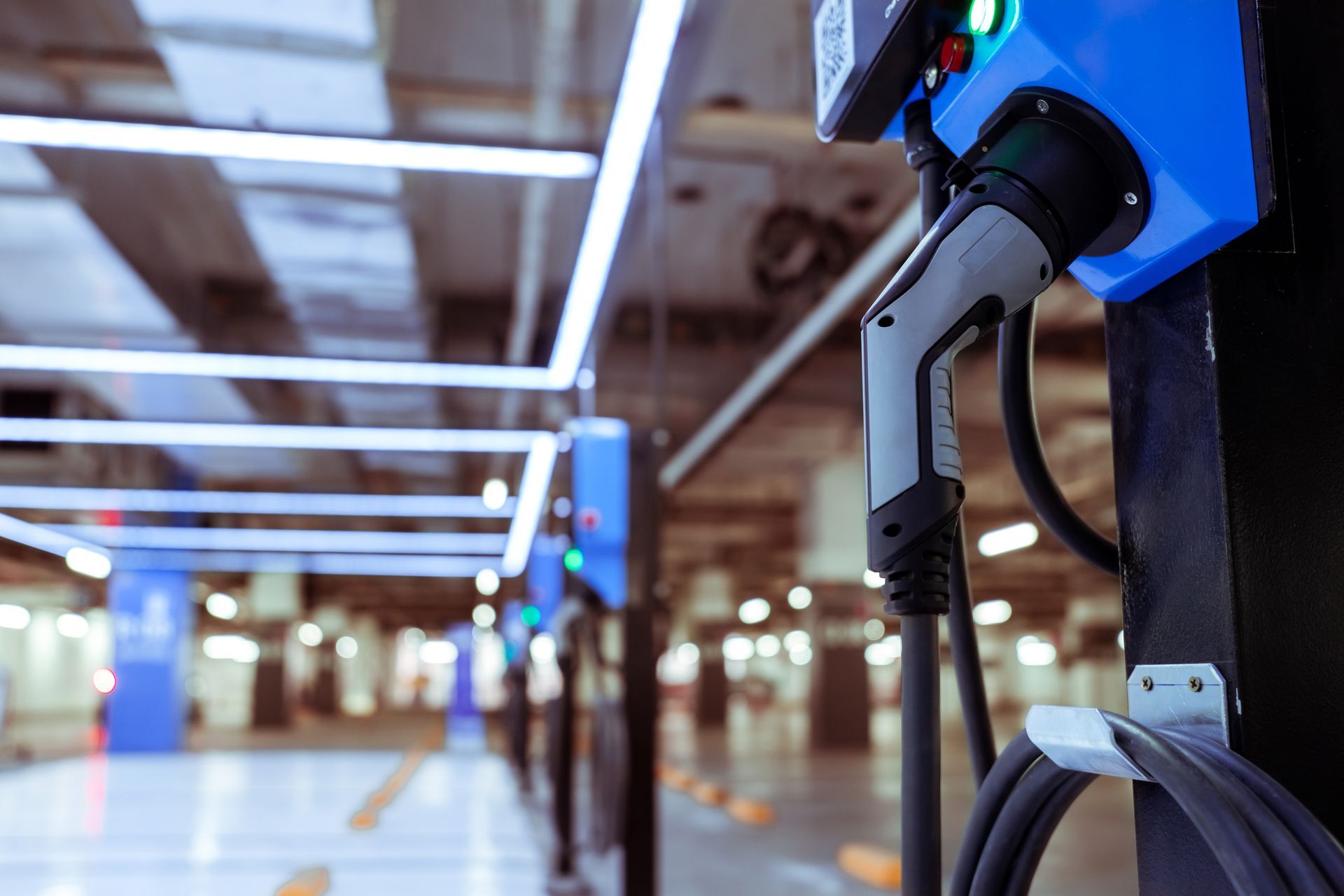 An electric car is being charged at a charging station in a parking garage.