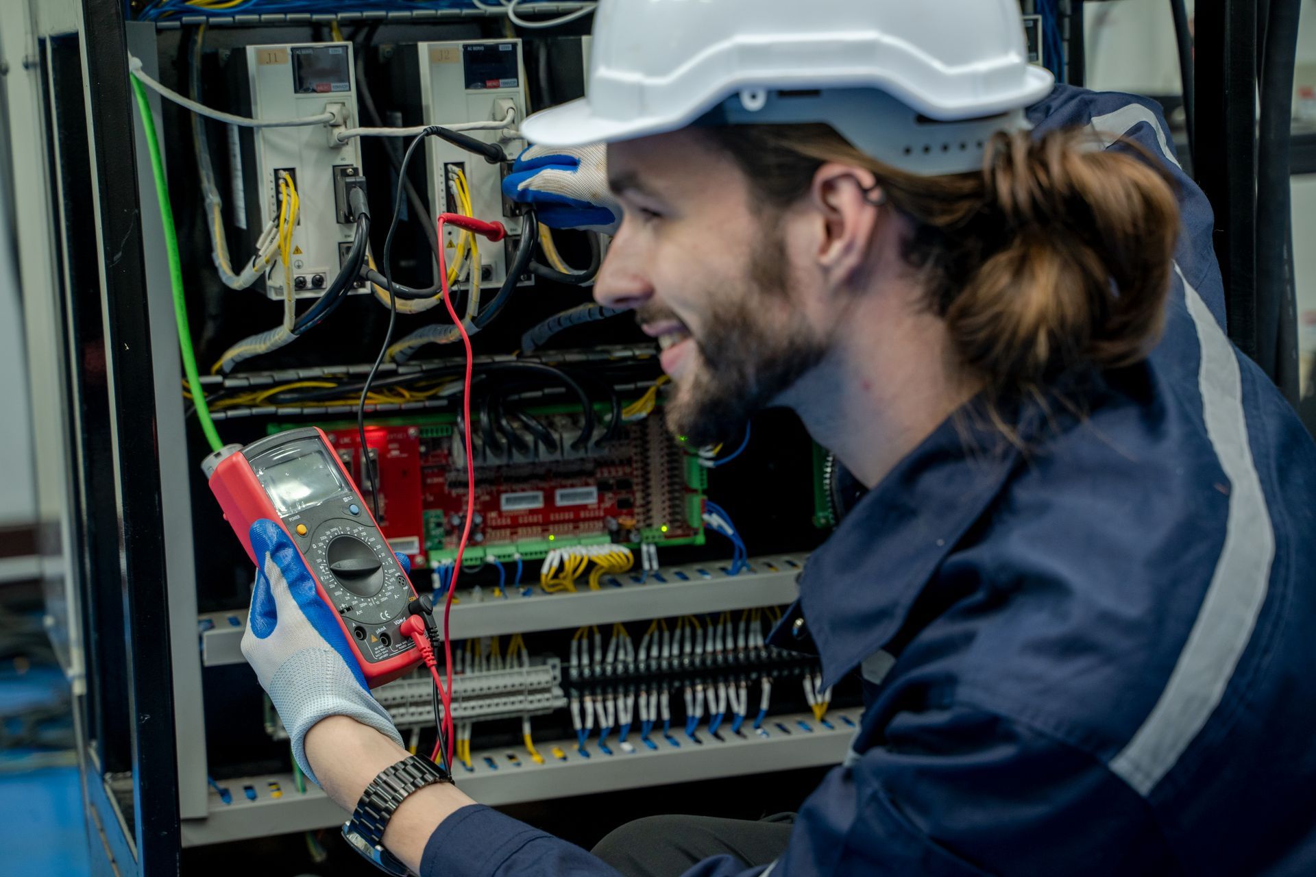 A man wearing a hard hat is working on a computer.