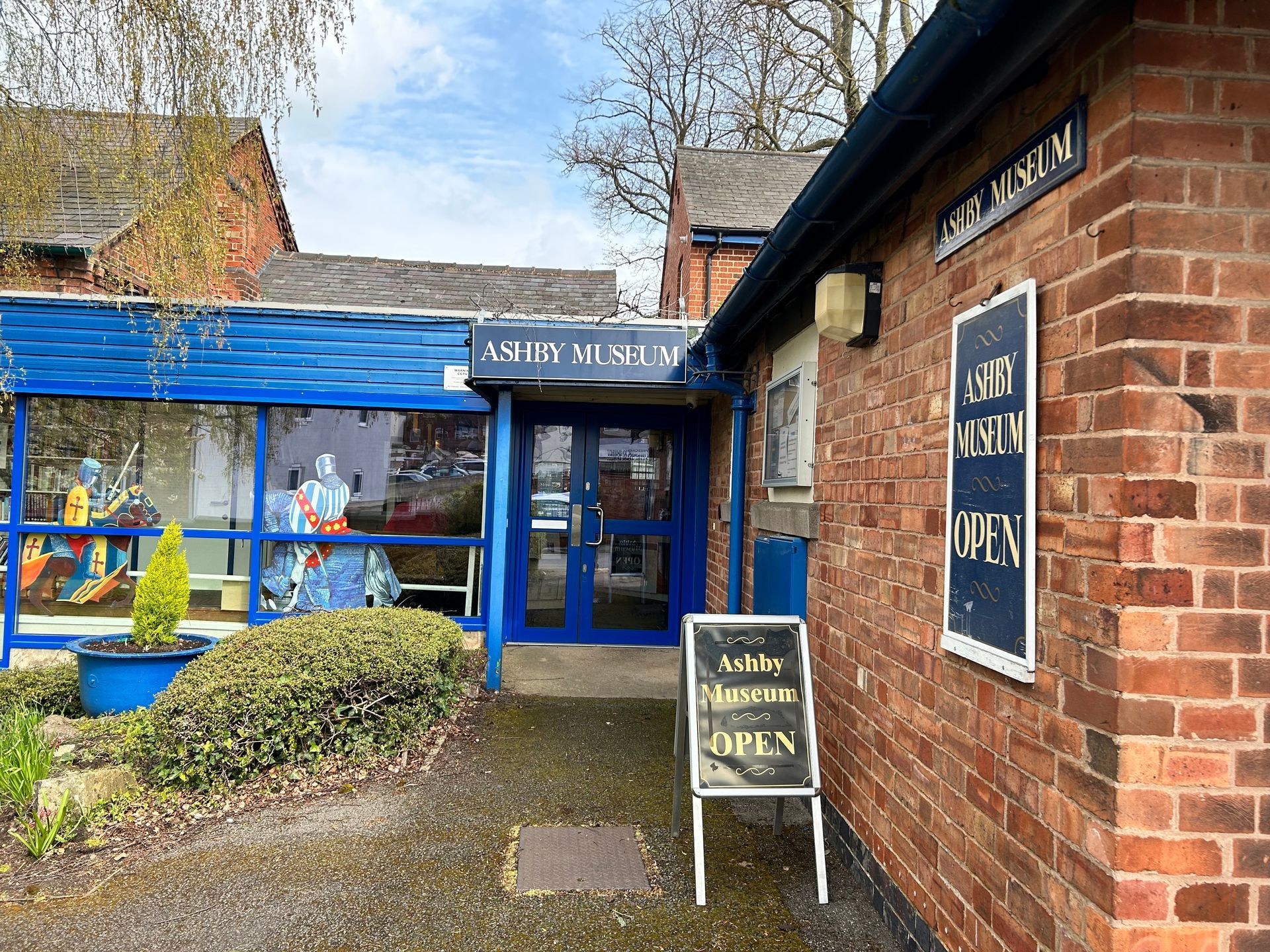 A brick building with a blue door and a sign that says open