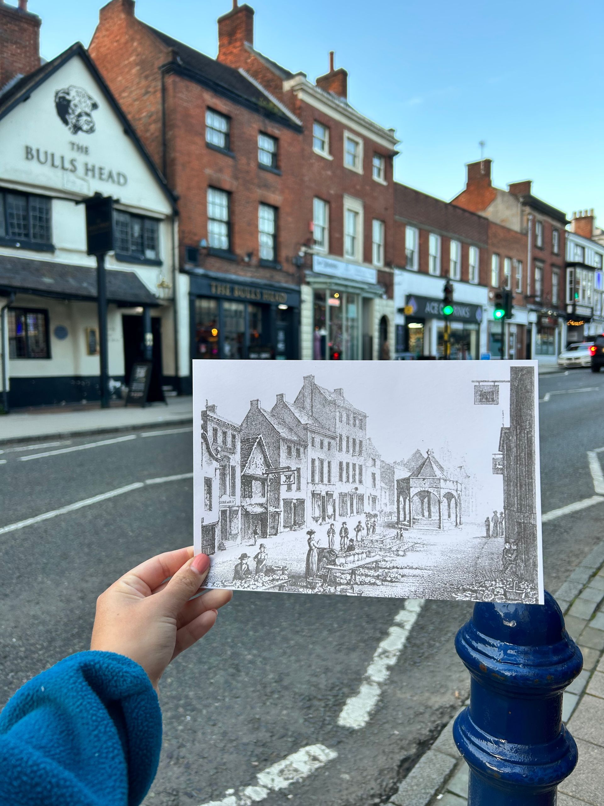 A person holding a drawing in front of a building that says bulls head