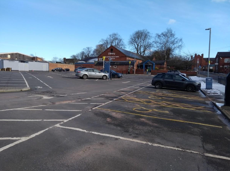 A parking lot with cars parked in it and a building in the background