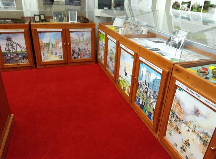 A room with a red carpet and wooden cabinets with pictures on them