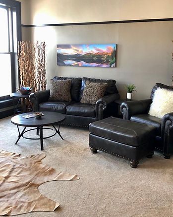 A living room with a couch , chair , coffee table and ottoman.