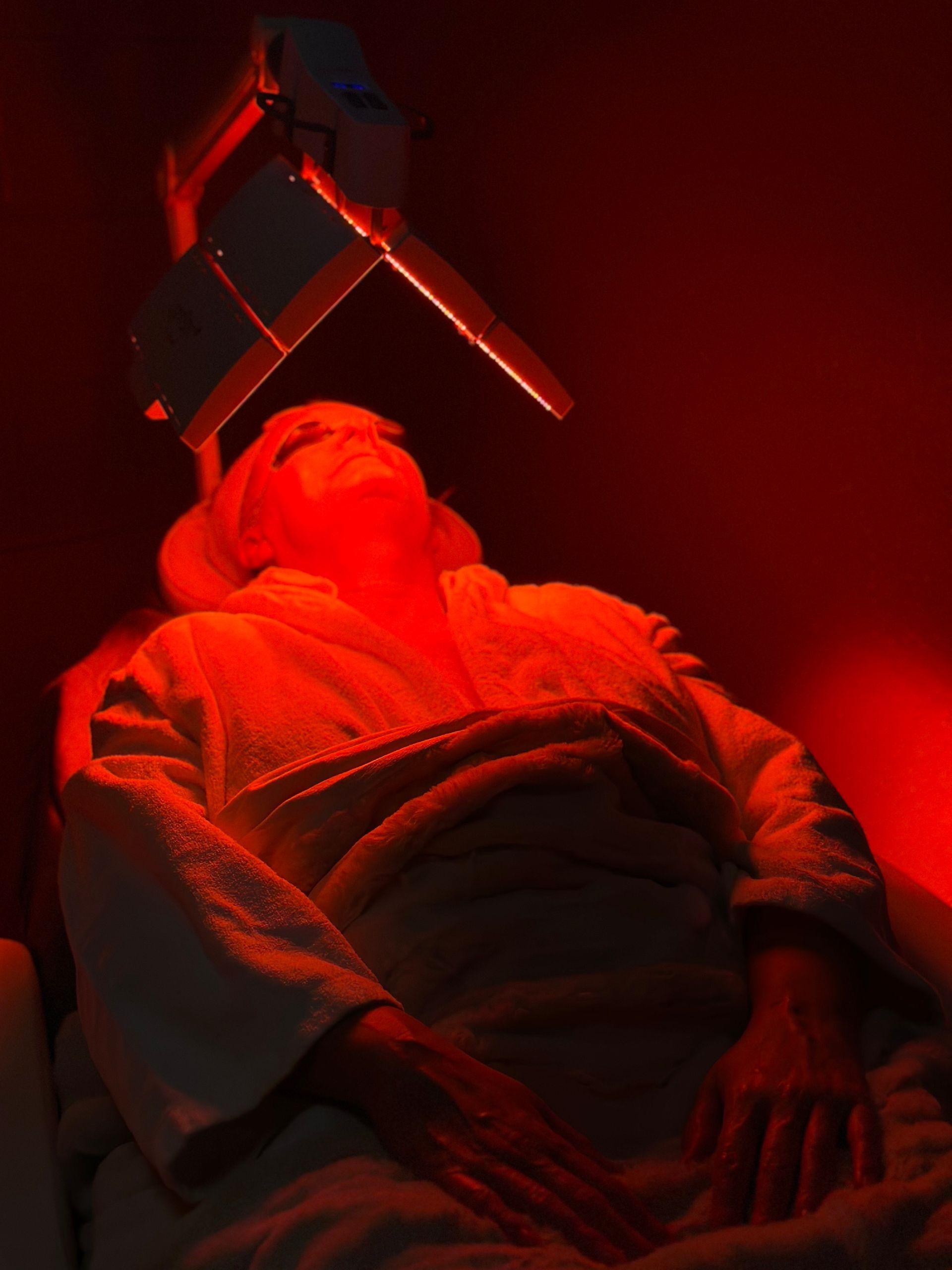 A woman is laying on a bed under a red light.