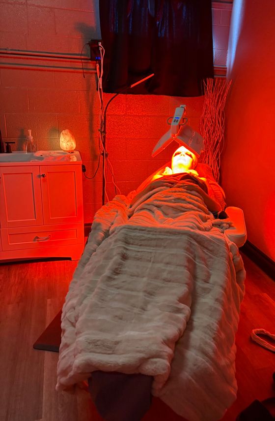 A person is laying on a bed with red light on their face.
