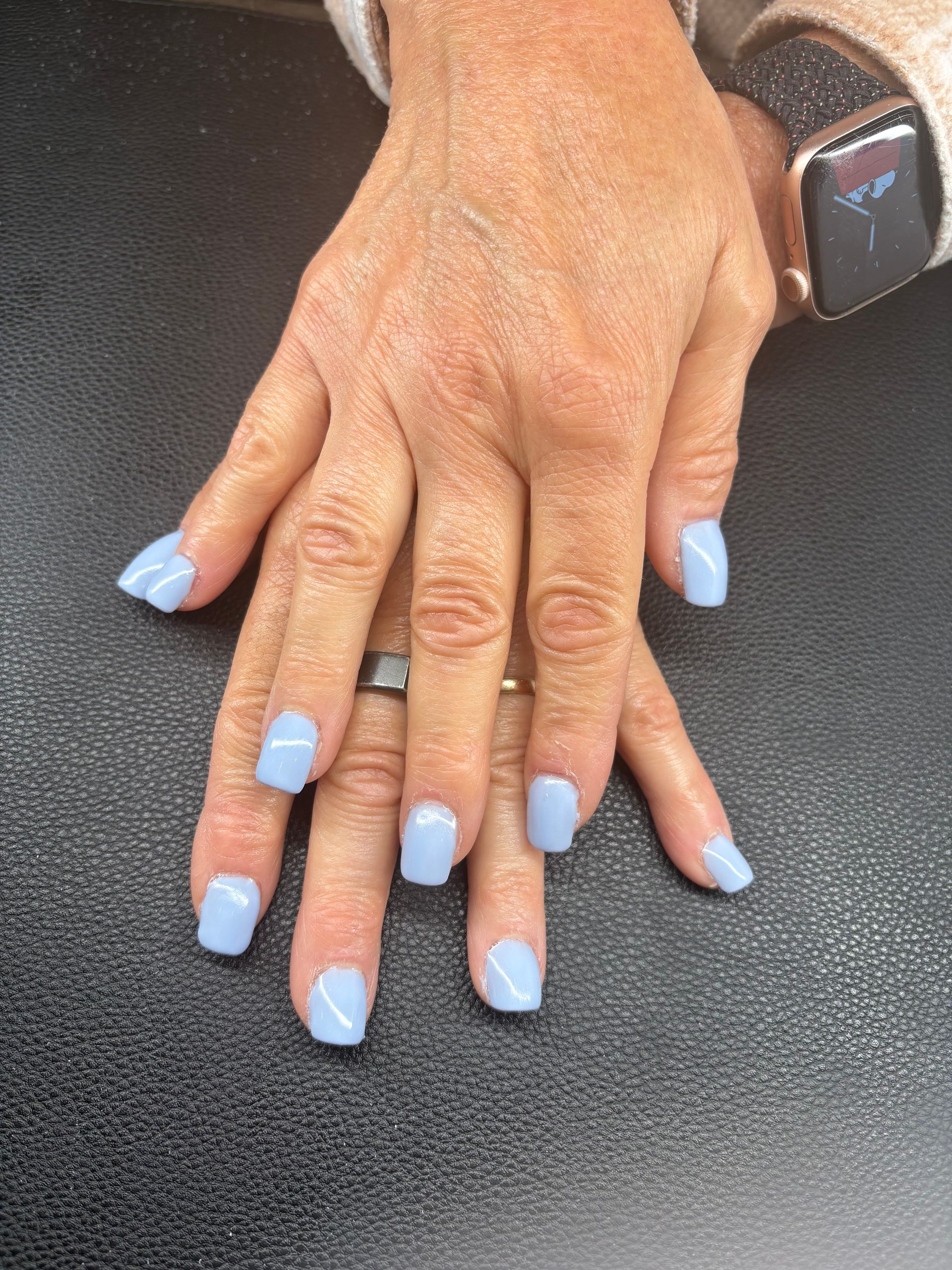 A woman 's hand with light blue nails and a watch on her wrist