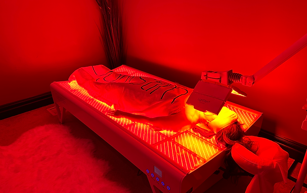 A person is laying on a bed under a red light.