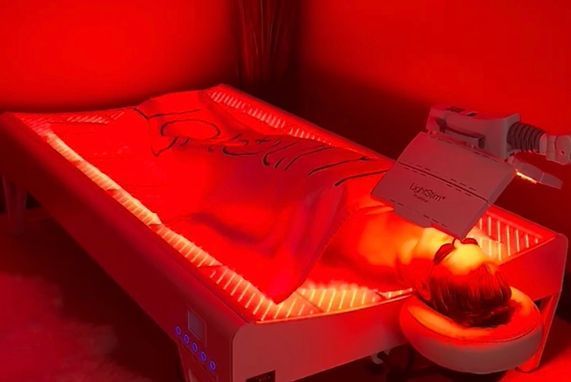 A person is laying on a bed with red lights on it.