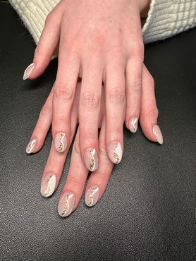 A close up of a woman 's hand with white and gold nails.