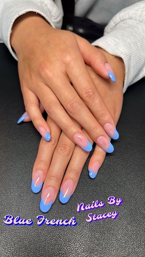 A close up of a person 's hands with blue french nails.