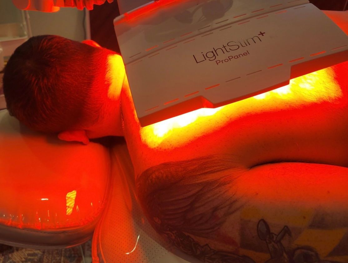 A man is laying under a machine that says lightsum on it