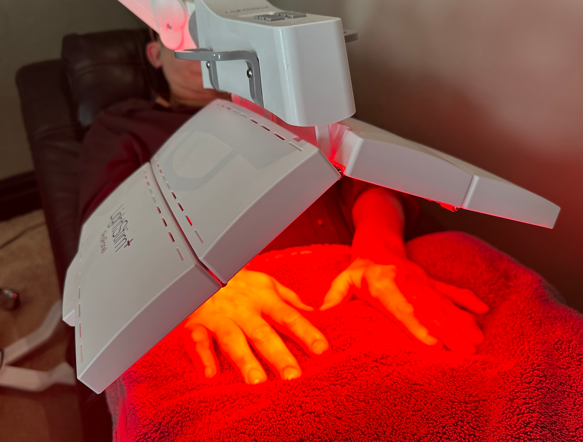 A person is getting a red light treatment on their hands