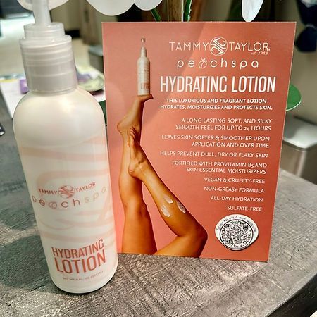 A bottle of tammy taylor peach spa hydrating lotion is sitting on a table next to a sign.