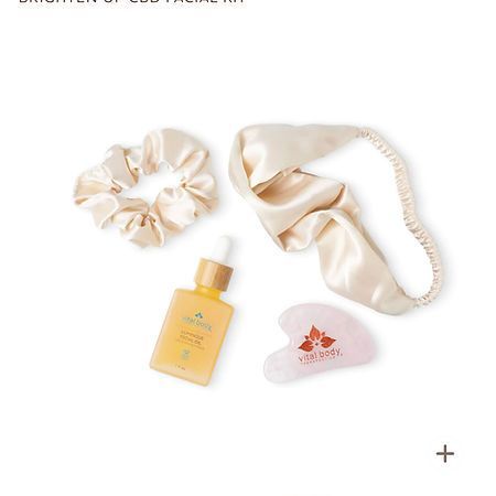 A bottle of serum , a scrunchie , and a gua sha on a white background.