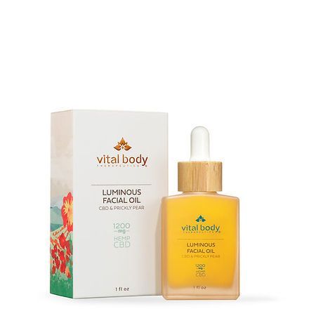 A bottle of vital body luminous facial oil next to a box.