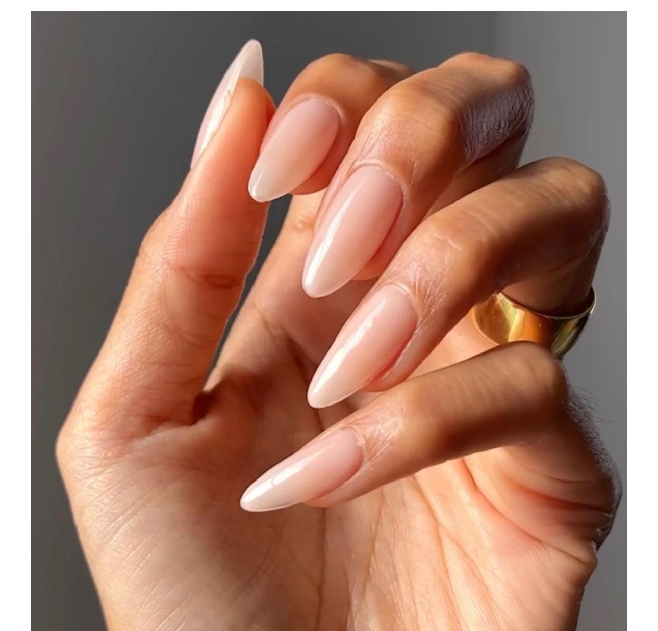 Hands with black, sparkly nail polish resting on a white surface, wearing a ring.