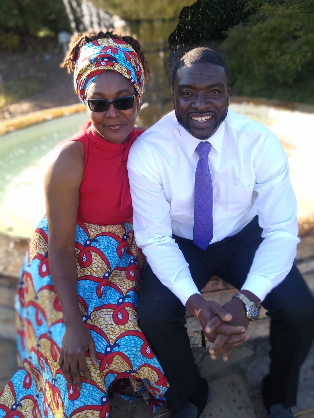 A man and a woman are posing for a picture in front of a fountain