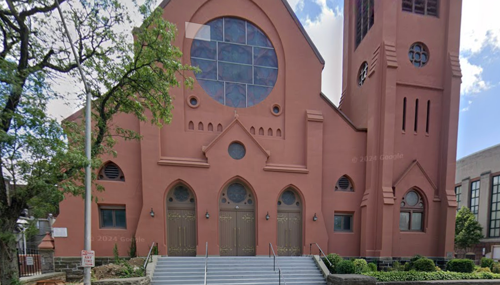 A large red church with a green roof and a clock tower.