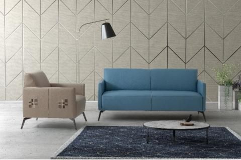 Un soggiorno con un divano blu, una sedia, un tavolino e un tappeto.