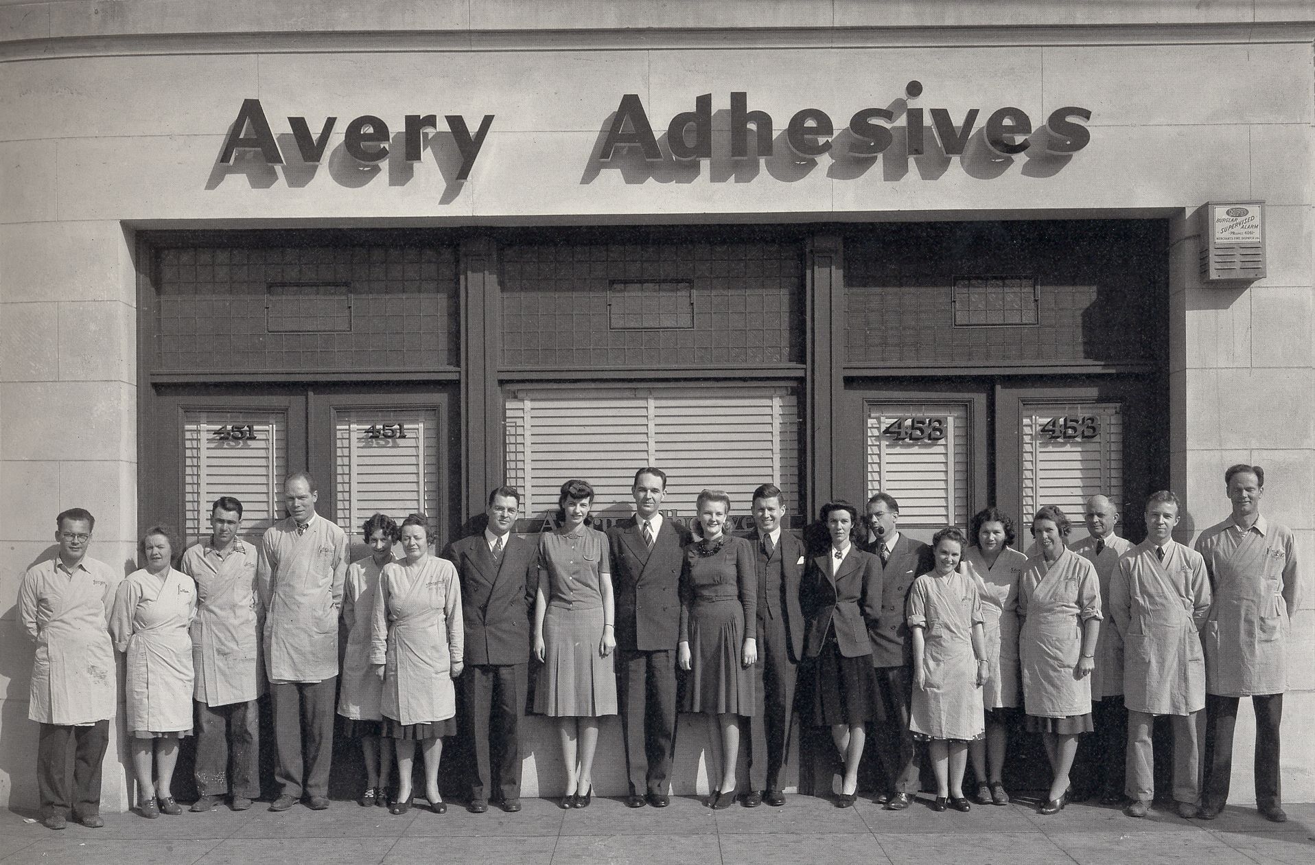 Un grupo de personas se encuentra frente a un edificio que dice Avery