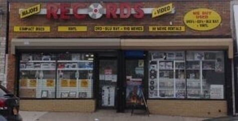 The front of a records store with cars parked in front of it
