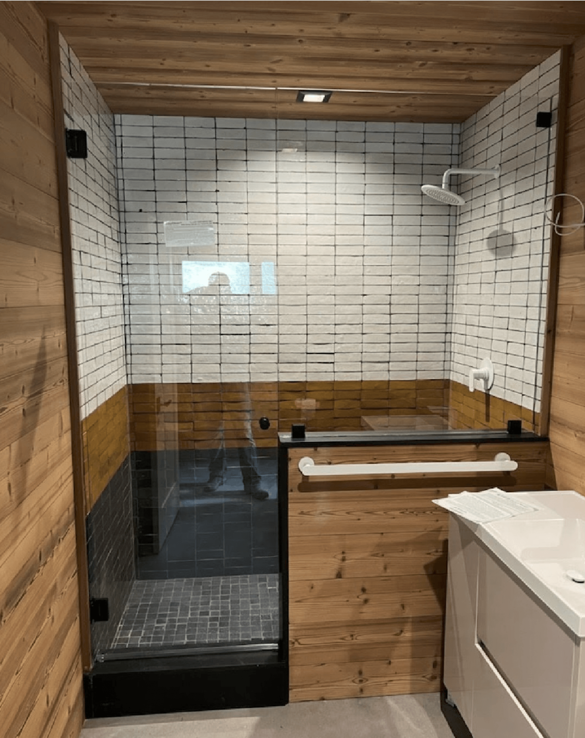 a bathroom with wooden walls, shower glass and a walk in shower 