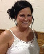 A woman in a white tank top is smiling for the camera.