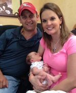 A man and a woman are sitting on a couch holding a baby.