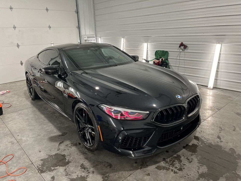 A black lamborghini urus is parked in a garage.