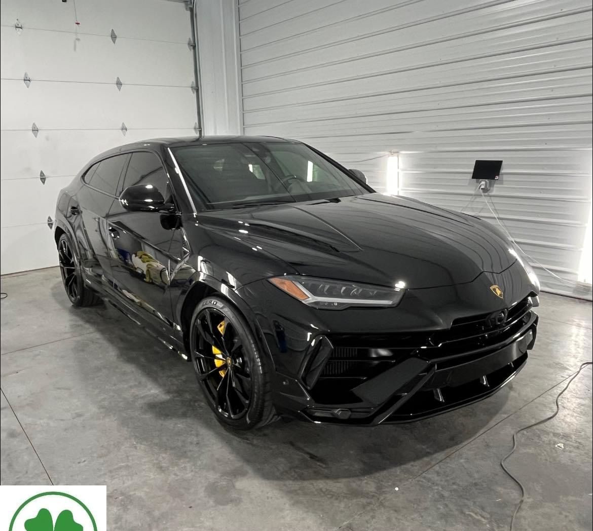 A black lamborghini urus is parked in a garage.